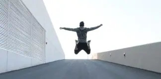 Man jumping on urban road with arms spread wide in Dubai, showcasing freedom and energy.