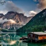 Peaceful mountain lake scene featuring a rustic boathouse and stunning reflections.