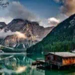 Peaceful mountain lake scene featuring a rustic boathouse and stunning reflections.