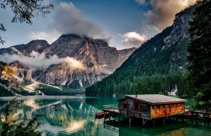 Peaceful mountain lake scene featuring a rustic boathouse and stunning reflections.