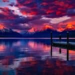 Stunning sunset over a serene lake with colorful sky and majestic mountains.