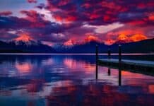 Stunning sunset over a serene lake with colorful sky and majestic mountains.