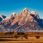 Breathtaking autumn landscape of Grand Teton with snow-capped peaks and colorful trees.