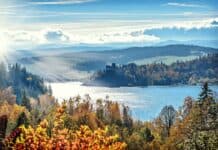 Stunning autumn scenery with sunlit lake and mountains, capturing nature's vibrant colors.