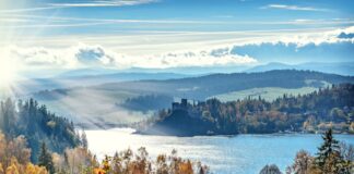 Stunning autumn scenery with sunlit lake and mountains, capturing nature's vibrant colors.